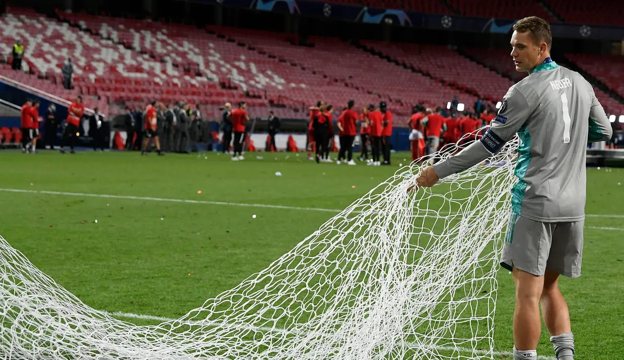 Kiper Bayern Munchen, Manuel Neuer membawa jaring gawang saat merayakan timnya meraih trofi Liga Champions usai mengalahkan PSG pada pertandingan final di stadion Luz di Lisbon (23/8/2020). Munchen menang tipis atas PSG 1-0. (AFP/Lluis Gene)