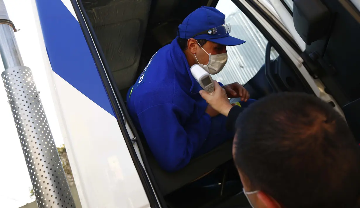 Yamil Peralta diperiksa suhunya di pintu masuk perusahaan tempatnya bekerja di Pilar, Buenos Aires, 28 Juli 2020. Di tengah lockdown, petinju profesional ini membuat alat olahraga darurat di rumahnya untuk berlatih dengan harapan lolos kualifikasi Olimpiade Tokyo 2021. (AP Photo/Marcos Brindicci)