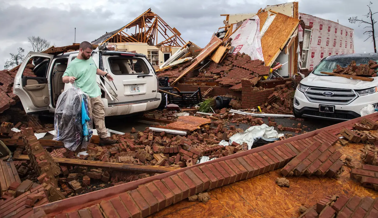 Ren mengambil pakaian dari mobilnya yang rusak akibat badai besar di Negara Bagian Georgia, Amerika Serikat, Minggu (22/1). Setidaknya 18 orang dilaporkan tewas akibat cuaca buruk yang memicu badai tornado. (AP Photo/Branden Camp)