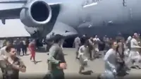 Ratusan orang berlari di samping pesawat angkut C-17 Angkatan Udara AS di landasan bandara internasional, di Kabul, Afghanistan (16/8/2021).  Ratusan warga Afghanistan berusaha kabur dari negaranya. Hal ini terjadi usai pemberontak Taliban menduduki ibu kota Afghanistan. (Verified UGC via AP)