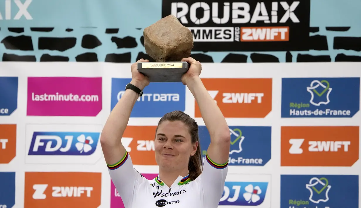 Pembalap Team SD Worx - Protime, Lotte Kopecky mengangkat trofi setelah memenangkan perlombaan balap sepeda Paris Roubaix Femmes 2024 yang menempuh 148,5km antara Denain hingga Roubaix, Prancis, Sabtu (06/07/2024) waktu setempat. (AFP/Christophe Ena)