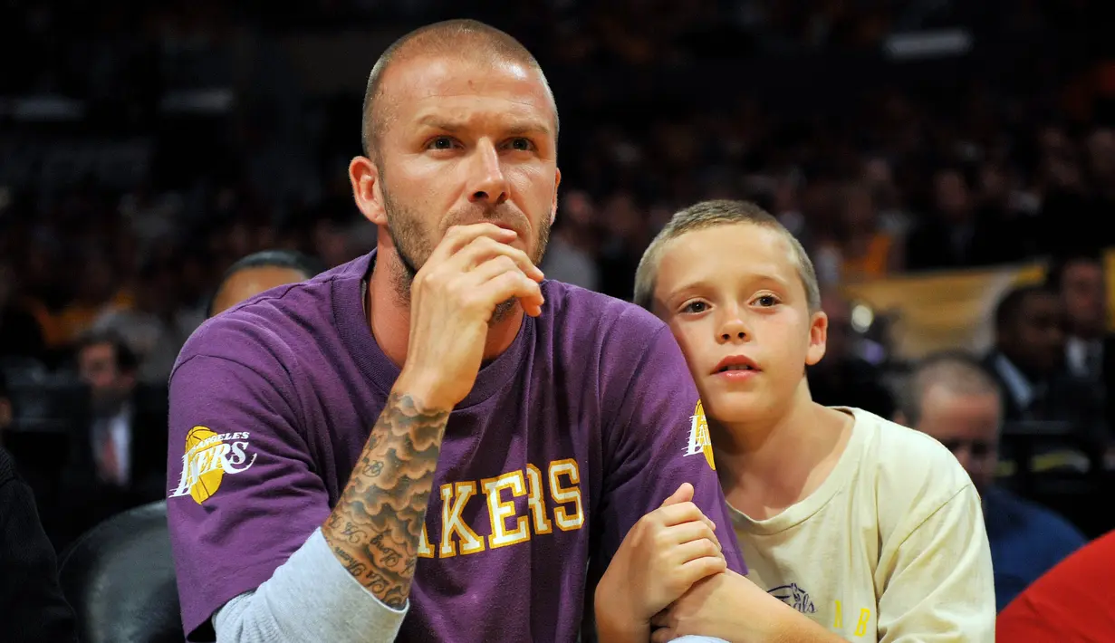 Legenda Timnas Inggris, David Beckham, bersama anaknya, Brooklyn, saat menyaksikan pertandingan NBA antara Boston Celtics melawan Los Angeles Lakers di Amerika Serikat, (10/6/2008). (Photo by GABRIEL BOUYS / AFP)