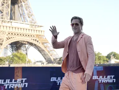 Aktor Hollywood Brad Pitt melambai saat sesi pemotretan untuk film 'Bullet Train' di Paris, Prancis, Sabtu (16/7/2022). Aktor berusia 58 tahun tersebut tampil kasual dengan blazer oranye cerah, celana panjang berwarna serasi, dan T-shirt. (AP Photo/Christophe Ena)