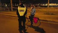 Polisi memeriksa seorang wanita yang mengendarai sepeda selama jam malam dekat Majelis Nasional di Paris, Perancis, Selasa (15/12/2020). Pelanggar jam malam akan dikenakan denda 135 Euro atau sekitar Rp 2,3 juta. (AP Photo/Francois Mori)