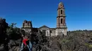 Wisatawan berjalan di dekat gereja San Juan Parangaricutiru di Angahuan, Meksiko, 17 Januari 2016. Gereja ini disebut sebagai keajaiban Tuhan karena luput dari sapuan lava gunung berapi pada  20 februari 1943 silam. (AFP PHOTO / Mario Vazquez)