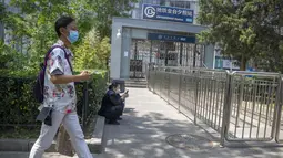 Seorang pria yang mengenakan masker berjalan melewati pintu keluar stasiun kereta bawah tanah yang tertutup di Beijing, China Rabu (4/5/2022). Beijing pada hari Rabu ini menutup lebih dari 40 stasiun kereta bawah tanah, sekitar sepersepuluh dari jaringan kereta, sebagai bagian dari tindakan untuk menghentikan penyebaran Covid-19. (AP Photo/Mark Schiefelbein)