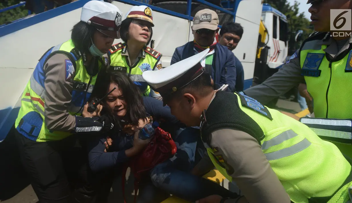 Petugas polisi berusaha mengamankan seorang wanita saat terjadi aksi demo di Jalan Medan Merdeka Barat, Jakarta, Rabu (28/3). Para driver taksi online ini menuntut Permenhub Nomor 108 Tahun 2017 dicabut. (Merdeka.com/Imam Buhori)