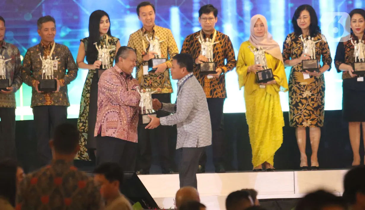 Gubernur Bank Indonesia Perry Warjiyo menyerahkan penghargaan BI Award 2019  kepada Direktur Bisnis Internasional dan Tresuri BNI Bob Tyasika Ananta (kanan) dalam acara Pertemuan Tahunan Bank Indonesia (PTBI) 2019 di Jakarta, Kamis (28/11/2019). (Liputan6.com/Angga Yuniar)