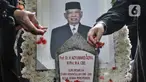 Warga menaburkan bunga saat berziarah ke makam Ketua Dewan Pers Azyumardi Azra di Taman Makam Pahlawan (TMP) Kalibata, Jakarta Selatan, Selasa (20/9/2022). Selain para tokoh dan cendekiawan, warga dari kalangan umum turut hadir di pemakaman Azyumardi Azra untuk berziarah sekaligus memberikan pengormatan terakhir. (merdeka.com/Iqbal S Nugroho)