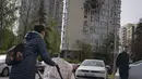 Orang-orang melewati sebuah gedung apartemen yang rusak akibat drone yang ditembak jatuh, selama serangan semalam Rusia, di Kyiv, Ukraina, Senin, 8 Mei 2023. (AP Photo/Andrew Kravchenko)