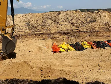 Puluhan jenazah dikubur massal menggunakan eskavator di TPU Peboya Indah, Palu, Sulawesi Tengah, Rabu (3/10). Jenazah yang merupakan korban gempa tsunami dikubur tiga lapis. (Liputan6.com/Fery Pradolo)