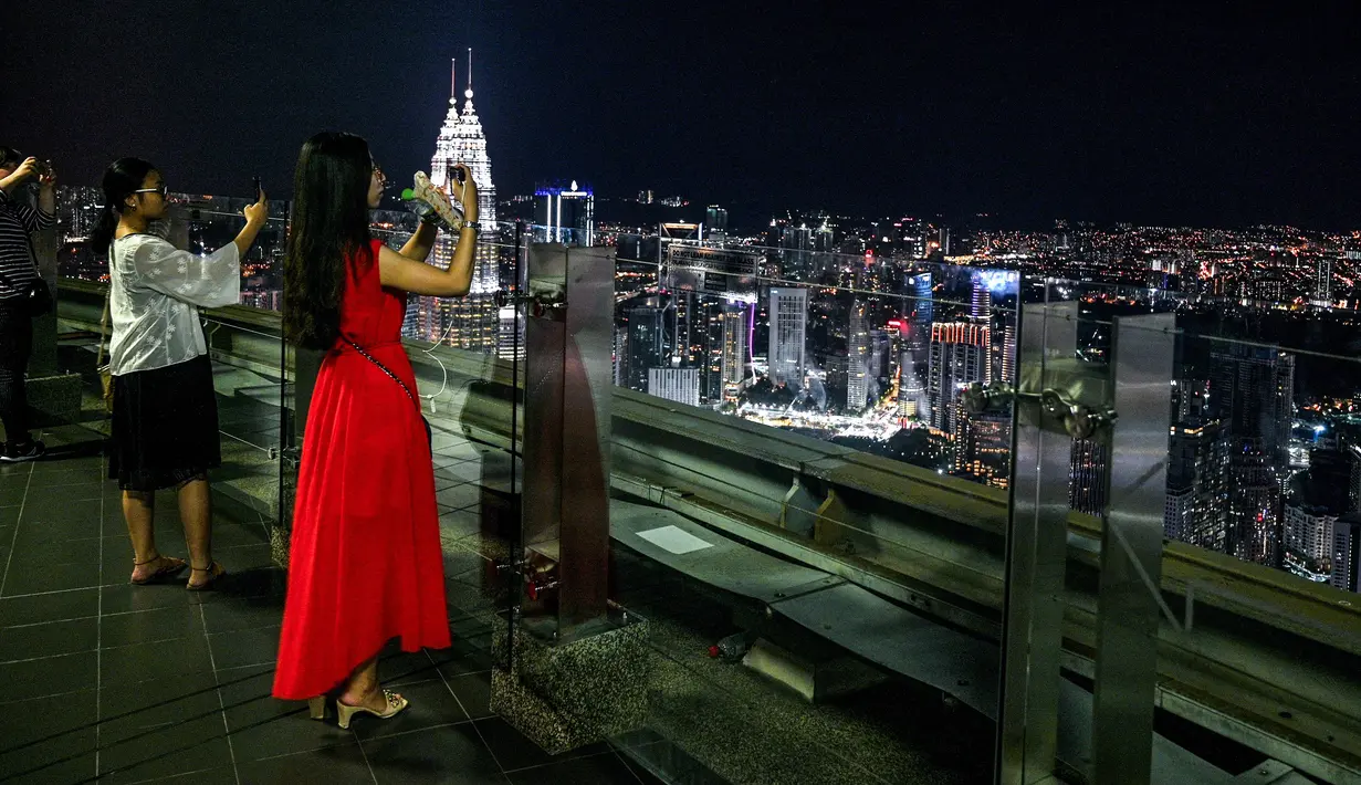 Gambar pada 14 Februari 2019 menunjukkan para turis mengambil gambar pemandangan cakrawala kota dari dek observasi Menara Kuala Lumpur di ibu kota Malaysia. Di sini pengunjung bisa mengamati segala penjuru kota Kuala Lumpur. (Mohd RASFAN / AFP)