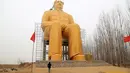 Seorang pria berada dibawah patung Presiden pertama Cina, Mao Zedong saat proses penyelesaian pembangunannya di ladang Desa Tongxu, Henan, Cina (4/1). Menurut warga, patung tersebut menghabiskan sekitar USD 460.000 atau Rp 6,4 miliar. (Reuters/Stringer)