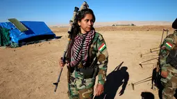Seorang pejuang wanita Iran-Kurdi berpakaian militer lengkap dengan senjatanya saat  pertempuran melawan kelompok radikal Negara Islam (ISIS) di Bashiqa, dekat Mosul, Irak, Kamis (3/11). (Reuters/Ahmed Jadallah)