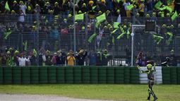 Setelah menyelesaikan seluruh balapan, The Doctor melewati seluruh tribune di sirkuit Misano dan langsung turun menghampiri para penggemarnya . Tak lupa Rossi melambaikan tangan sebagai ucapan terimakasih kepada para penggemarnya. (AFP/Andreas Solaro)