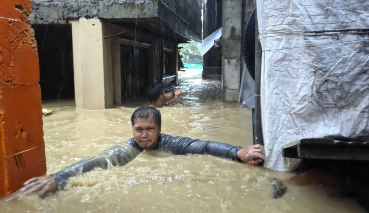 Seorang pria mengatasi banjir setinggi leher di desanya yang disebabkan oleh Topan Doksuri di kota Laoag, provinsi Ilocos Norte, Filipina utara, Rabu, 26 Juli 2023. (AP Photo/Bernie Sipin Dela Cruz)