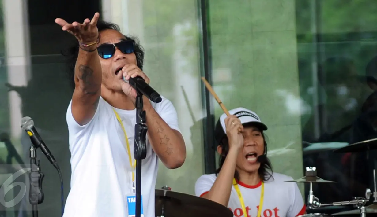 Vokalis Slank, Kaka bernyanyi saat menggelar konser di halaman Gedung KPK, Jakarta, Senin (22/2). Slank memberikan dukungan kepada lembaga antirasuah itu dengan menolak rencana revisi UU No 30 Tahun 2002 tentang KPK. (Liputan6.com/Helmi Afandi)