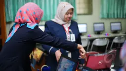 Sejumlah Guru mempersiapkan komputer untuk ujian nasional (UN) di SMA 70, Jakarta, Senin (13/4/2015). Sebanyak 585 dari 70 ribu sekolah menjadi percontohan menjalankan ujian nasional berbasis komputer di seluruh Indonesia.  (Liputan6.com/Faizal Fanani)