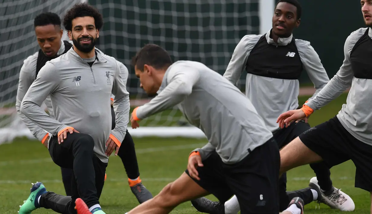 Gelandang Liverpool, Mohamed Salah (kiri) tersenyum saat melakukan pemanasan selama latihan jelang menghadapi Manchester City pada leg pertama perempatfinal Liga Champions di Melwood Training Ground di Liverpool, Inggris (3/4). (AFP Photo/Paul Ellis)