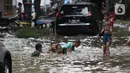 Anak anak bermain air di sebagian Jalan Bungur Besar Raya yang tergenang, Jakarta, Selasa (18/1/2022). Genangan air di sebagian Jalan Bungur Besar Raya dimanfaatkan anak-anak untuk bermain meski berbahaya. (Liputan6.com/Helmi Fithriansyah)