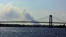 Asap mengepul di kejauhan sebelum Long Island dan Throgs Neck Bridge 11 September 2001 antara Bronx dan Queens, NY, menyusul penghancuran menara kembar World Trade Center. Sebuah serangan teroris yang meratakan dua bangunan. (AFP/Matt Campbell)