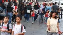 Pejalan kaki melintasi jalur masuk dan keluar Taman Fatahilah saat uji coba simulasi di kawasan Kota Tua, Jakarta, Selasa (23/4). Penataan akses tersebut dilakukan untuk memperlancar keluar masuknya pengunjung ke kawasan wisata tersebut. (Liputan6.com/Immanuel Antonius)
