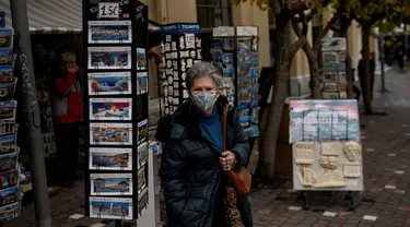 Seorang perempuan dengan masker berjalan di dekat Monastiraki square, pusat kota Athena, Yunani, Rabu (29/12/2021). WHO memperingatkan Organisasi Kesehatan Dunia (WHO) memperingatkan lonjakan kasus Covid-19 varian Omicron dapat menyebabkan fasilitas kesehatan kewalahan. (Angelos Tzortzinis/AFP)