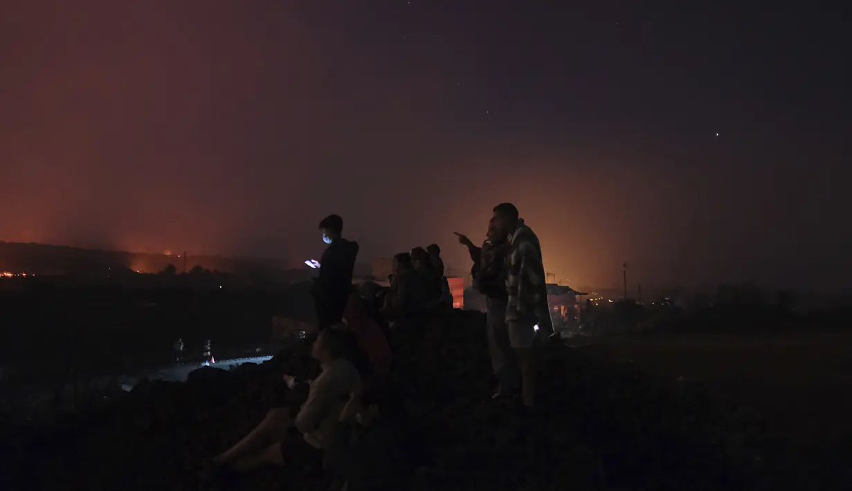 Orang-orang melihat ke gunung berapi Cumbre Vieja yang terus meletus di pulau Canary La Palma, Spanyol pada Sabtu (16/10/2021). Para pejabat mengatakan tidak ada tanda-tanda bahwa letusan gunung berapi di pulau La Palma Spanyol akan segera berakhir, satu bulan setelah dimulai. (AP Photo/Daniel Roca)