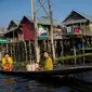 Masyarakat melewati rumah-rumah panggung menggunakan perahu di kampung terapung Danau Inle, Negara Bagian Shan, Myanmar, Senin (18/2). Seluruh kehidupan warga praktis berhubungan dengan perairan Danau Inle. (Ye Aung THU/AFP)