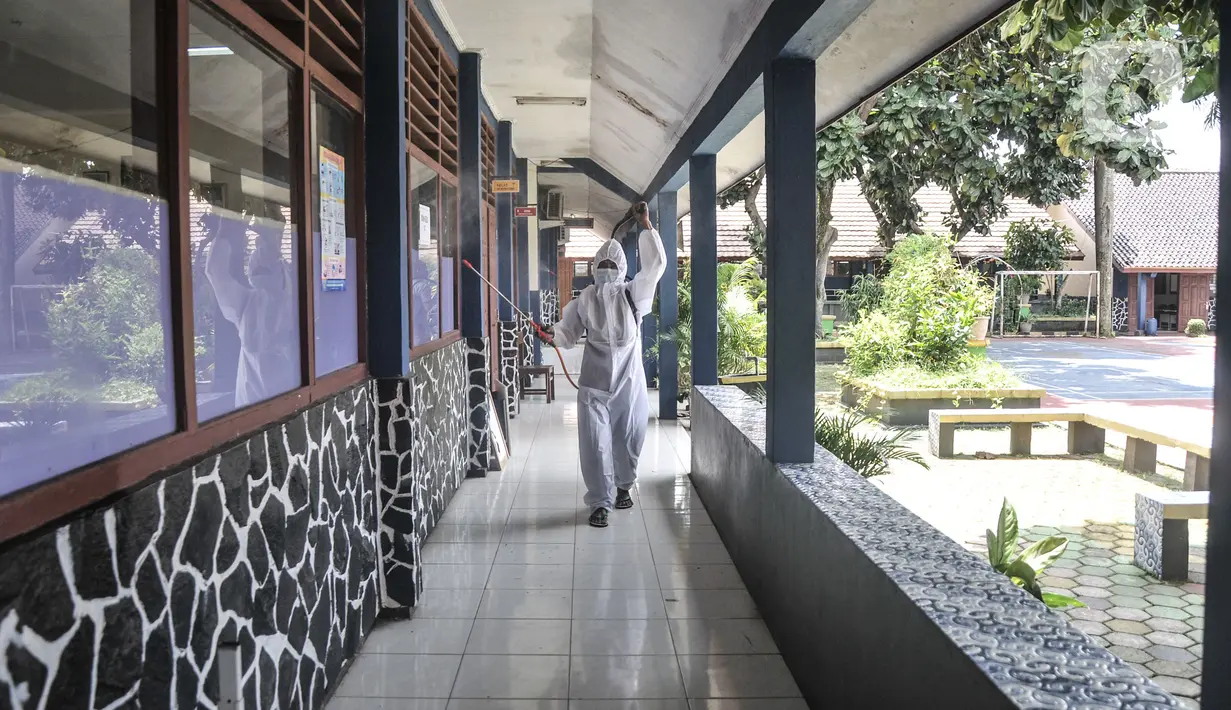Petugas sekolah menyemprotkan disinfektan di koridor usai Pembelajaran Tatap Muka (PTM) 100 persen di SMP Negeri 9 Depok, Cipayung, Senin (24/1/2022). Pihak sekolah melakukan penyemprotan disinfektan secara rutin seiring dimulainya pelaksanaan PTM 100 persen di Depok. (merdeka.com/Iqbal S Nugroho)