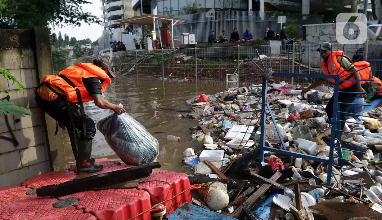 Petugas UPK Badan Air DLH Provinsi DKI Jakarta berjibaku membersihkan tumpukan sampah yang menghalangi aliran air Kali Mampang di Jalan Pejaten Raya, Jakarta, Sabtu (20/2/2021). Aliran air Kali Mapang di Jalan Pejaten Raya meluap akibat sumbatan tumpukan sampah. (Liputan6.com/Helmi Fithriansyah)