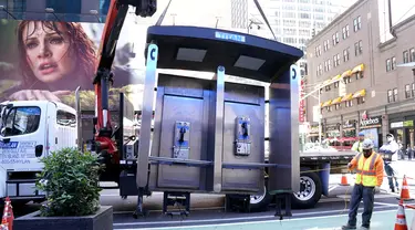 Para pekerja memindahkan bilik telepon umum terakhir NYC di dekat Seventh Avenue dan 50th Street di Midtown Manhattan, New York City, Amerika Serikat (AS) pada 23 Mei 2022. Menandai berakhirnya sebuah era, Kota New York pada hari Senin menghapus bilik telepon umum yang telah menjadi "korban" karena kemunculan teknologi informasi seperti Wi-Fi gratis dan telepon seluler. (TIMOTHY A. CLARY / AFP)