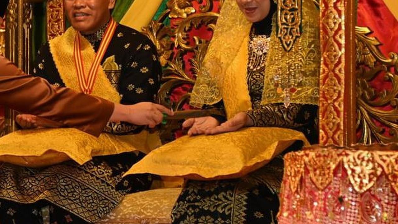 Sang istri pun tampak anggun mempesona memakai busana yang didominasi warna hitam dan emas tersebut.<br>