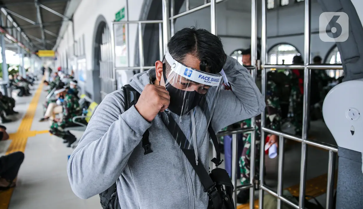 Penumpang menggunakan pelindung wajah berjalan di Stasiun Pasar Senen, Jakarta Pusat, Jumat (10/7/2020). PT. KAI membagikan face shield kepada penumpang bertujuan memudahkan masyarakat tetap dapat menjaga physical distancing di tengah pandemi COVID-19. (Liputan6.com/Faizal Fanani)