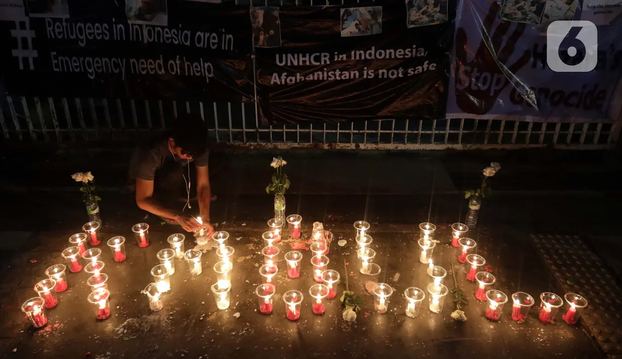 Seorang pencari suaka menyalakan lilin membentuk nama kota di Afghanistan saat aksi keprihatinan yang digelar di depan kantor UNHCR, Jakarta, Selasa (11/5/2021). Mereka prihatin atas peristiwa serangan bom yang menewaskan puluhan siswi di Kabul, Afghanistan. (Liputan6.com/Helmi Fithriansyah)
