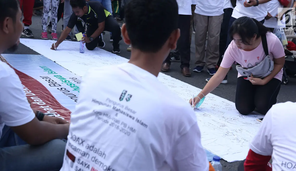 Warga menandatangani spanduk dukungan anti hoax di kawasan Bundaran Hotel Indonesia, Jakarta, Minggu (18/11). PB HMI mensosialisasikan Hoax sebagai ancaman demokrasi di Indonesia. (Liputan6.com/Helmi Fithriansyah)