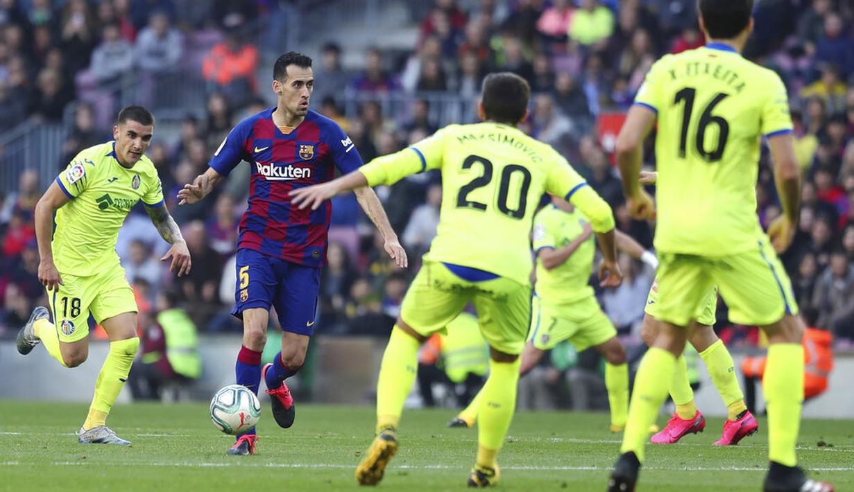 Gelandang Barcelona, Sergio Busquets, berusaha melewati pemain Getafe pada laga La Liga di Stadion Camp Nou, Sabtu (15/2/2020). Barcelona menang 2-1 atas Getafe. (AP/G.Garin)