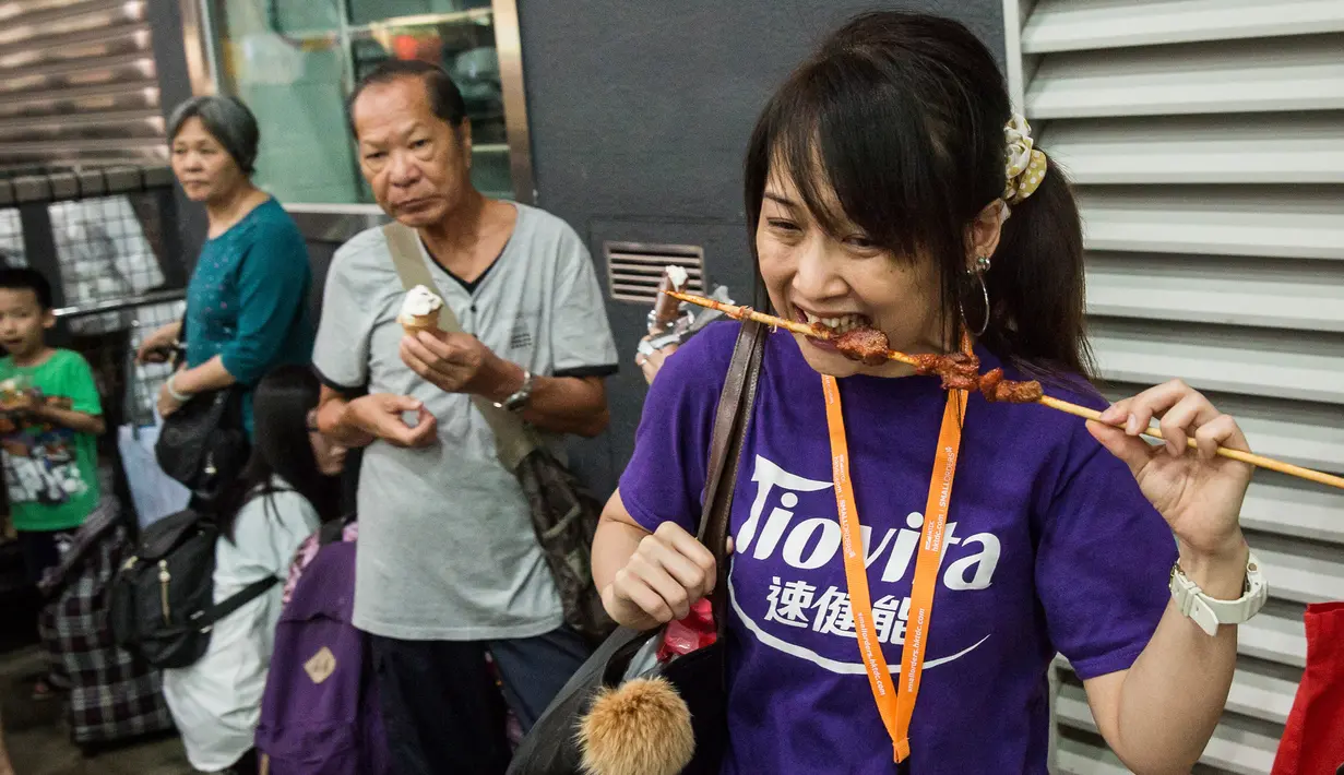 Seorang pengunjung menikmati sate daging di Food Expo di Hong Kong (19/8). Pameran makanan tahunan ini diadakan di Hong Kong Exhibition and Convention Center dan berlangsung dari 17-21 Agustus. (AFP Photo/Isaac Lawrence)