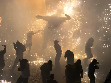 Sejumlah pengunjung berlari di dekat kembang api yang meledak dari banteng "Torito" dalam perayaan tradisional tahunan San Juan de Dios di Tultepec, Meksiko (8/3). (AP Photo/Rebecca Blackwell)