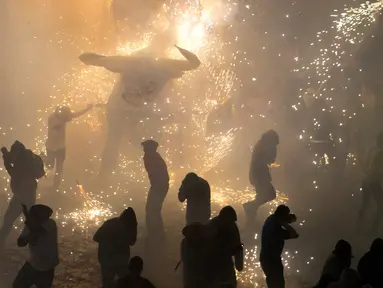 Sejumlah pengunjung berlari di dekat kembang api yang meledak dari banteng "Torito" dalam perayaan tradisional tahunan San Juan de Dios di Tultepec, Meksiko (8/3). (AP Photo/Rebecca Blackwell)