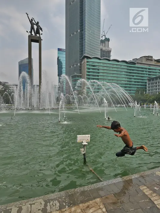 Seorang anak melompat ke kolam di Bundaran HI, Jakarta, Senin (17/6/2019). Meski ada larangan berenang, sejumlah anak tetap nekat menyebur ke kolam Bundaran HI. (Liputan6.com/Herman Zakharia)