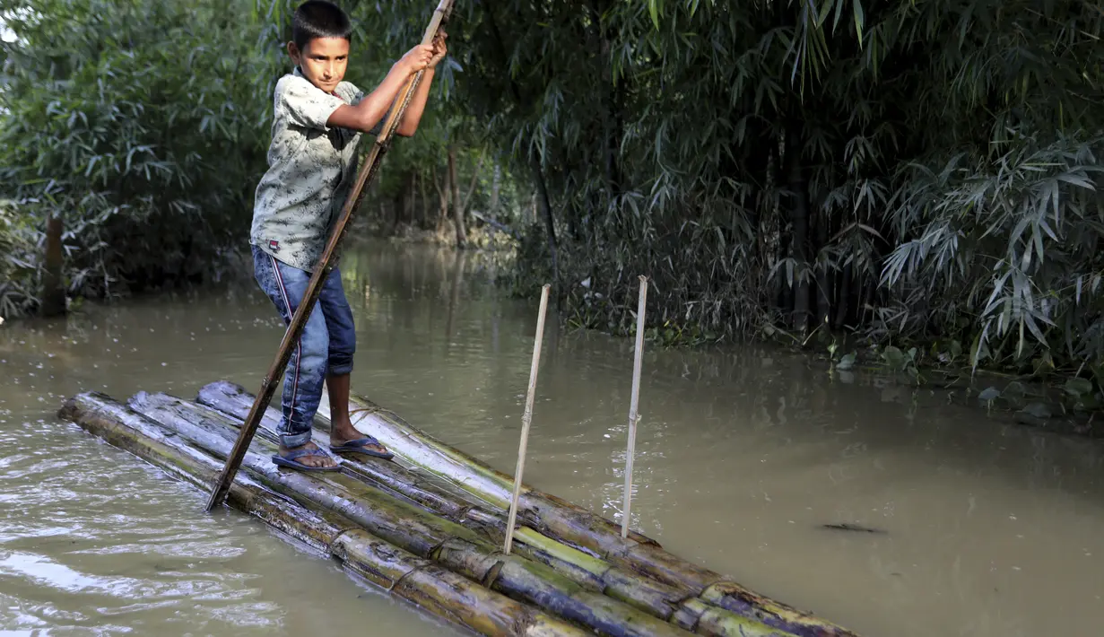 Seorang anak laki-laki berjalan dengan rakit bambu melalui air banjir di daerah Kanaighat di Sylhet, Bangladesh (23/5/2022). Banjir bandang pra-musim telah membanjiri bagian dari India dan Bangladesh, menewaskan sedikitnya 24 orang dalam beberapa pekan terakhir dan mengirim 90.000 orang ke tempat penampungan. (AP Photo)