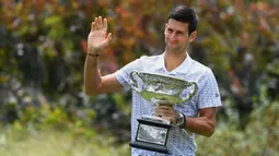 Petenis Serbia, Novak Djokovic memegang piala juara tunggal putra Australia Terbuka 2020 saat sesi pemotretan di Royal Botanic Gardens Victoria, Melbourne, Australia, Senin (3/2/2020). Bagi Novak Djokovic, ini merupakan gelar Australia Terbuka kedelapan. (Photo by William WEST / AFP)
