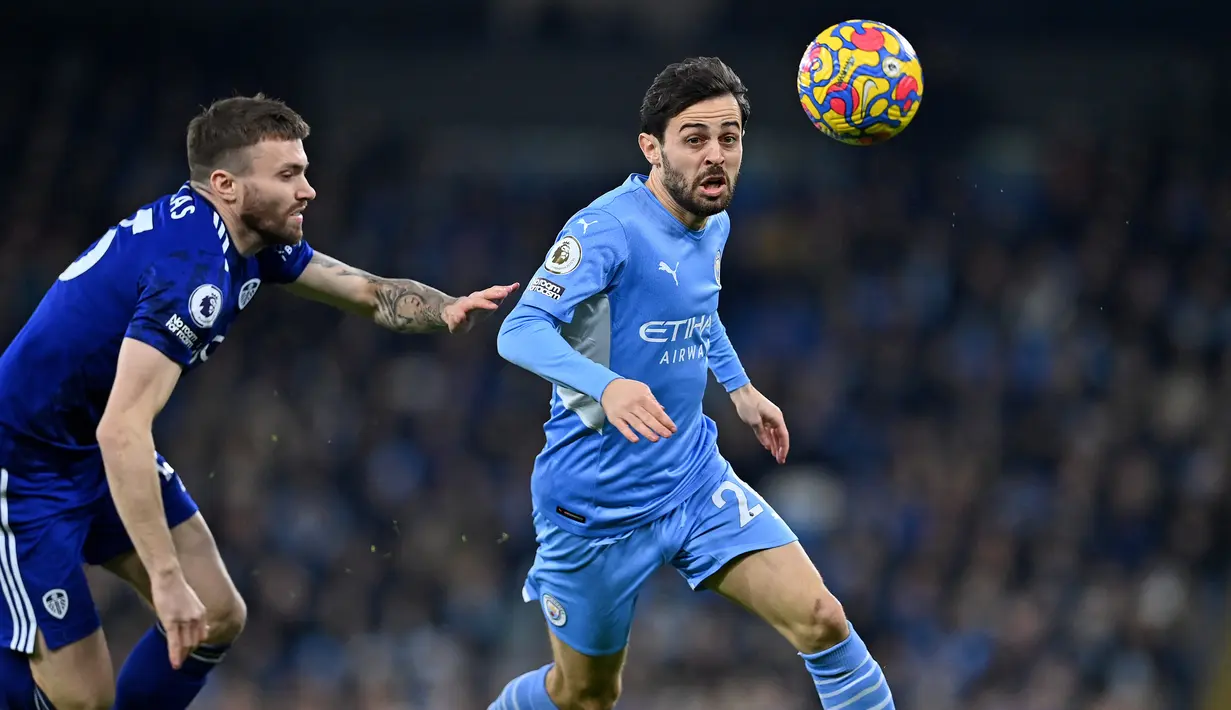 Gelandang Leeds United Stuart Dallas (kiri) berebut bola dengan gelandang Manchester City Bernardo Silva dalam laga pekan ke-17 Liga Inggris di Etihad Stadium, Rabu (15/12/2021) dini hari WIB. Manchester City mencukur tamunya Leeds United tujuh gol tanpa balas. (Paul ELLIS /AFP)