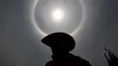 Seorang pria mengunakan topi saat berada di bawah 'Halo Matahari' di Mexico City, Kamis (21/5/2015). Menurut ahli meteorologi, fenomena cuaca menciptakan pelangi mengelilingi matahari dan dibentuk oleh refleksi dari kristal es. (REUTERS/Edgard Garrido)