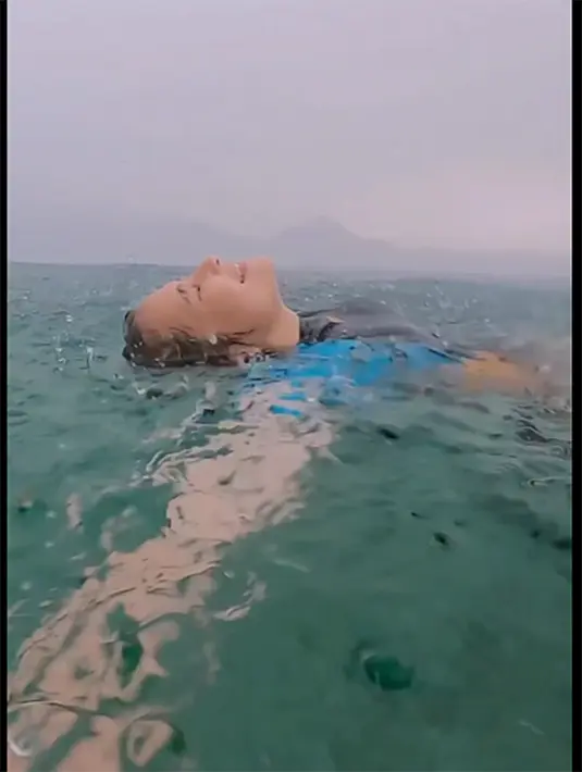 Melalui keterangan video yang dibagikan, Prilly mengaku mendapatkan pengalaman yang luar biasa ketika renang dengan guyuran rintik hujan. [Instagram/prillylatuconsina96]