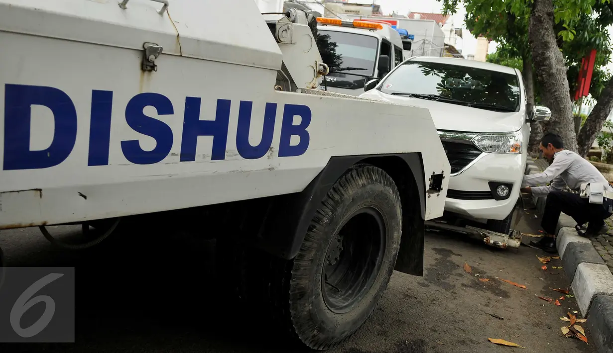 Petugas Dishub DKI saat melakukan penderekan terhadap mobil yang parkir liar di kawasan Pasar Baru, Jakarta, Senin (27/6). Penertiban rutin ini dilakukan untuk membuat efek jera bagi warga yang masih parkir sembarangan. (Liputan6.com/Gempur M Surya)