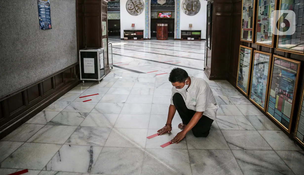 Petugas memasang tanda batas shaf di Masjid Cut Meutia, Jakarta, Kamis (30/7/2020). Masjid Cut Meutia akan menggelar Salat Idul Adha esok hari dengan menerapkan protokol kesehatan pencegahan Covid-19. (Liputan6.com/Faizal Fanani)