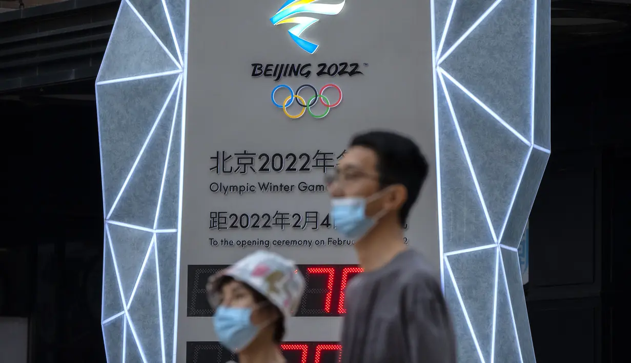 Orang-orang yang memakai masker untuk melindungi diri dari COVID-19 berjalan melewati layar yang menunjukkan jam hitung mundur ke Olimpiade Musim Dingin 2022 di Beijing (18/8/2021).  Pejabat tinggi Beijing menegaskan kembali perlunya anti-pencegahan yang ketat. (AP Photo/Mark Schiefelbein)