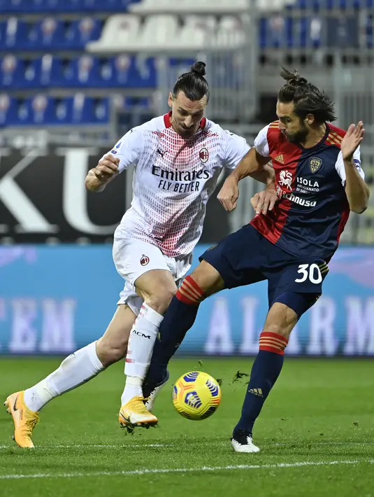Penyerang AC Milan, Zlatan Ibrahimovic berusaha melewati pemain Cagliari, Leonardo Pavoletti pada pertandingan Liga Serie A Italia di Sardegna Arena, Selasa (19/1/2021). Zlatan Ibrahimovic mencetak brace pertamanya di tahun 2021. (AFP/Alberto Pizzoli)